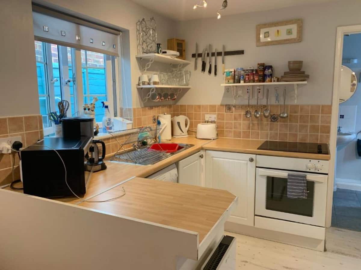 Halzephron House's guest kitchen with oven, hob and open shelving