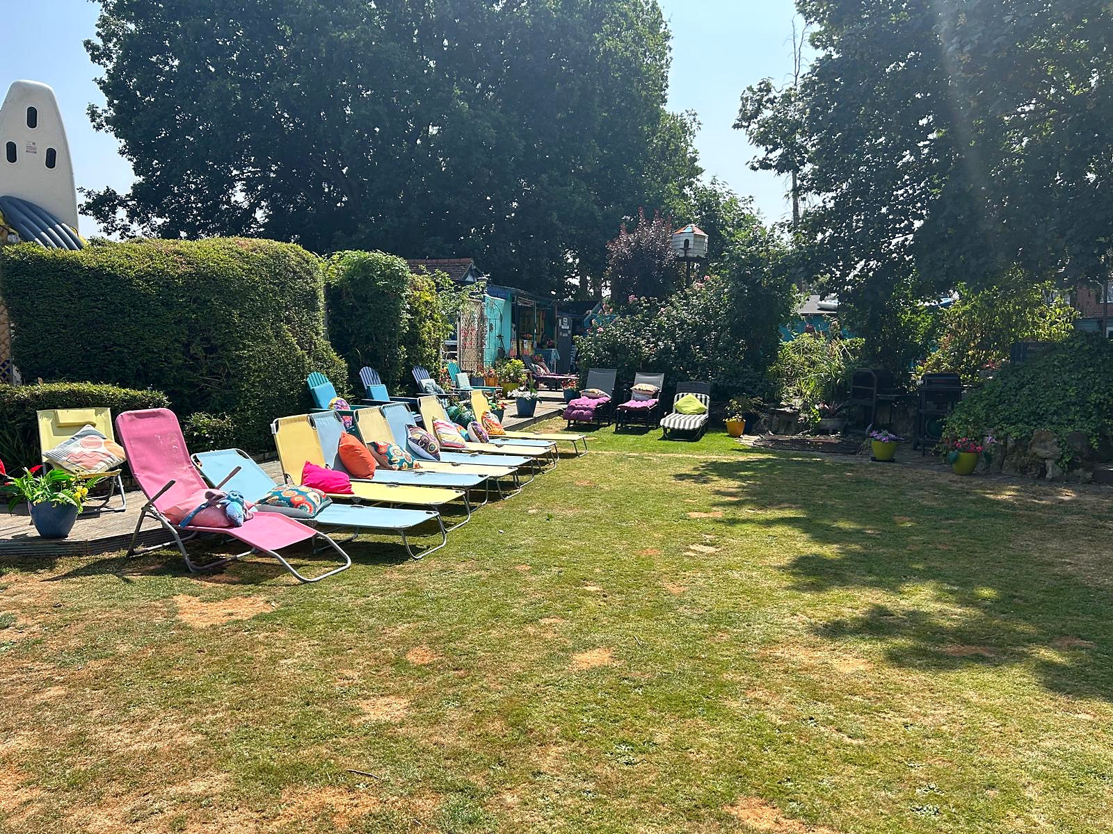 Wide view across Halzephron House's large guest garden with colourful loungers and seating