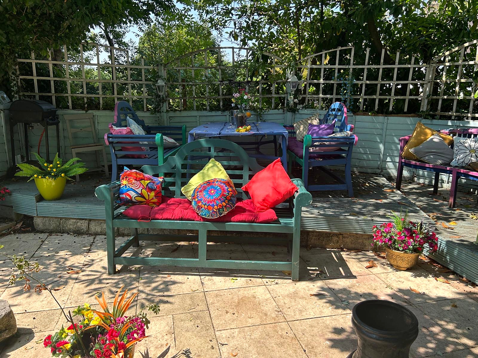Shaded seating and dining area beneath the trees in Halzephron House's garden