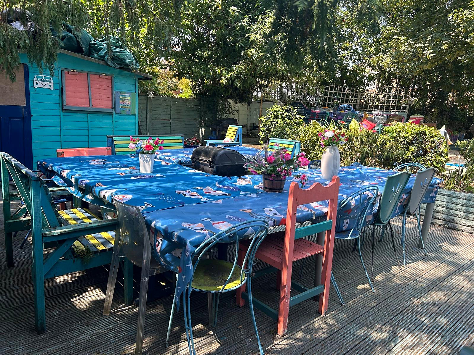 Large outdoor dining tables and colourful chairs in Halzephron House's garden